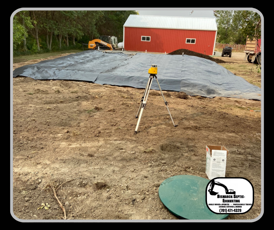 A tripod is sitting in the dirt in front of a red barn.
