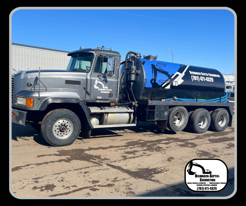 A vacuum truck is parked in a dirt lot in front of a building.