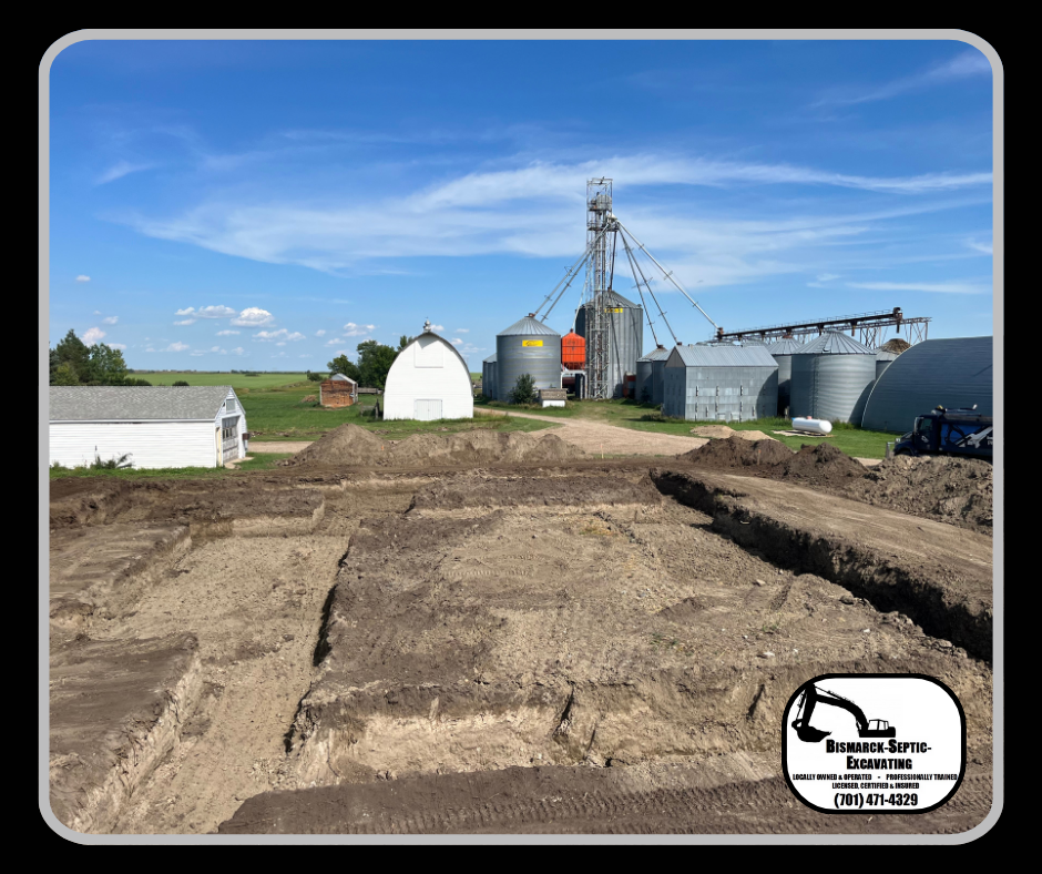 A large dirt field with a grain silo in the background.