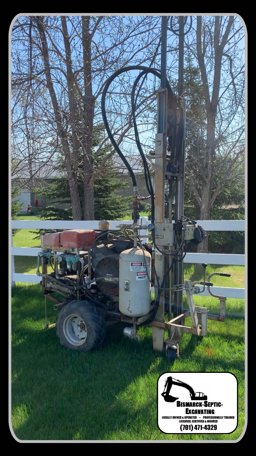 A machine is sitting in the grass next to a white fence.
