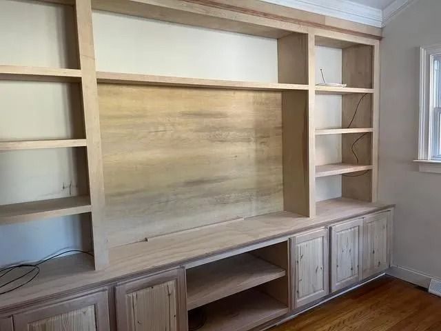 Built-in wood entertainment center with shelves and cabinets in a bright room