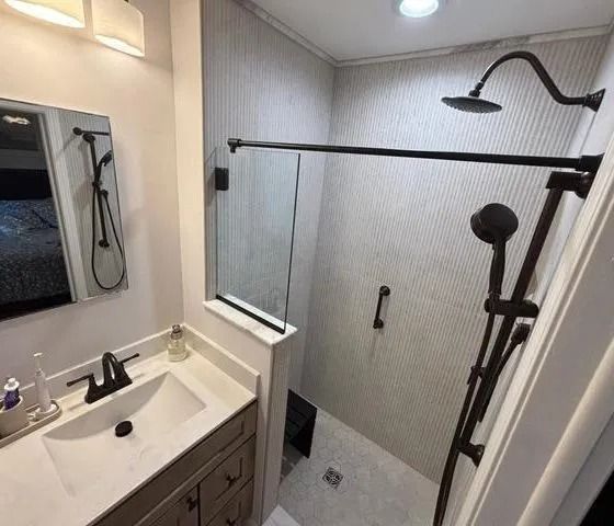Accessible bathroom with sink, mirror, and walk-in shower with grab bar and handheld showerhead