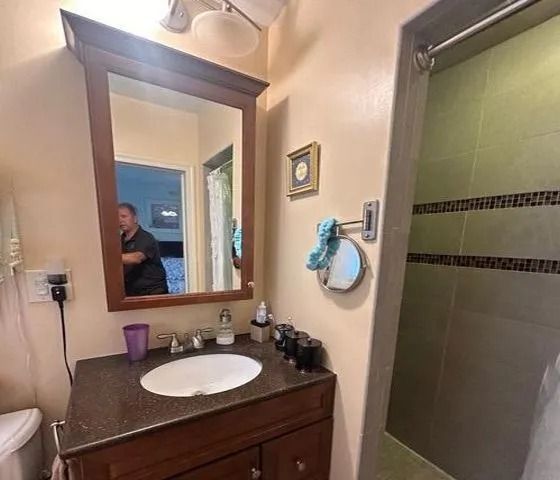 Bathroom vanity with mirror, white sink, and glass shower stall beside it.