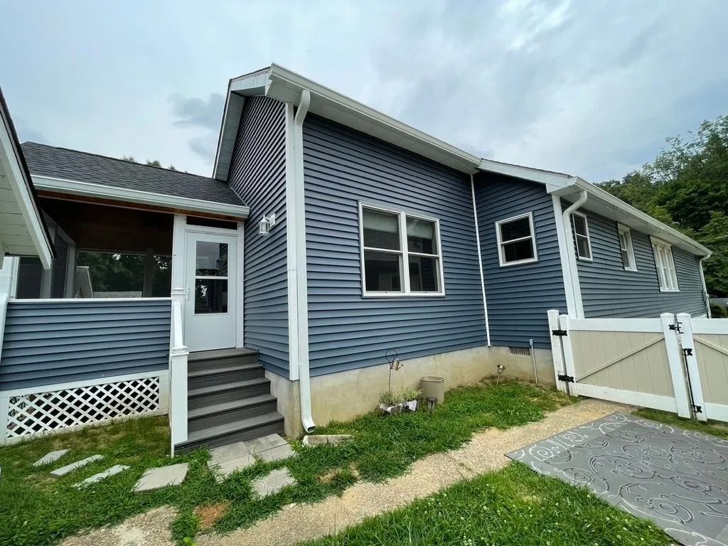 Blue house exterior with front steps, white trim, and gravel driveway