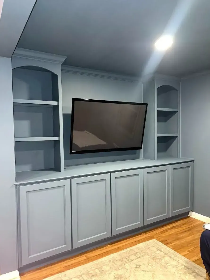 Built-in gray cabinetry with a wall-mounted TV in a bright room