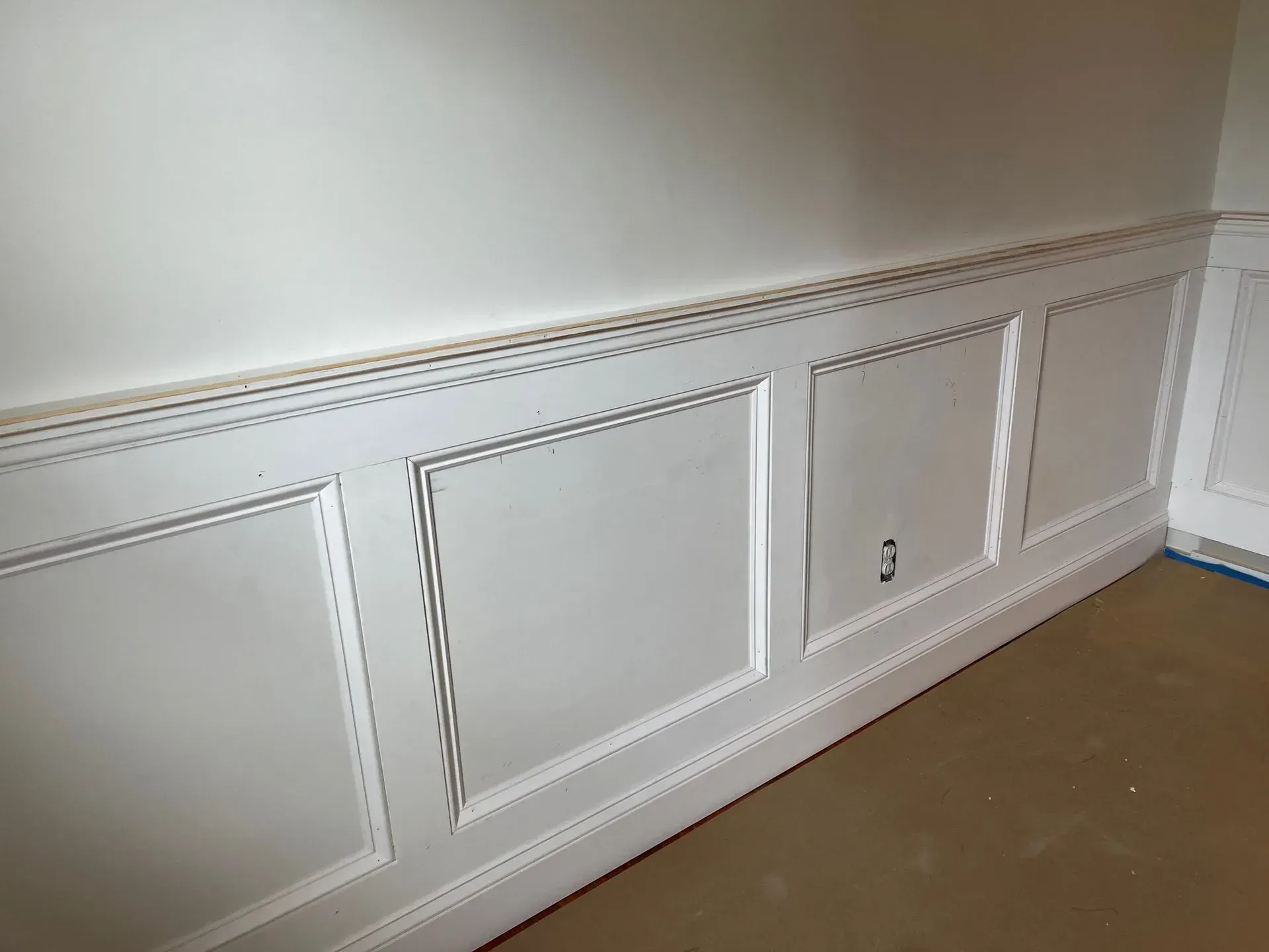 White wainscoting with decorative wall panels and molding in an empty room.