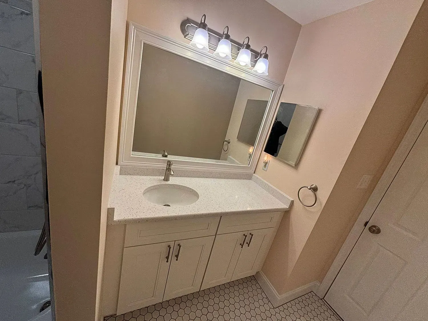 Bathroom vanity with white sink, mirror, and vanity lights against beige walls
