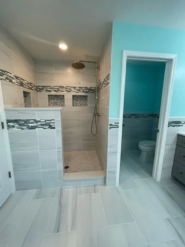 Bathroom with tiled shower, turquoise walls, and an open doorway to a toilet room.
