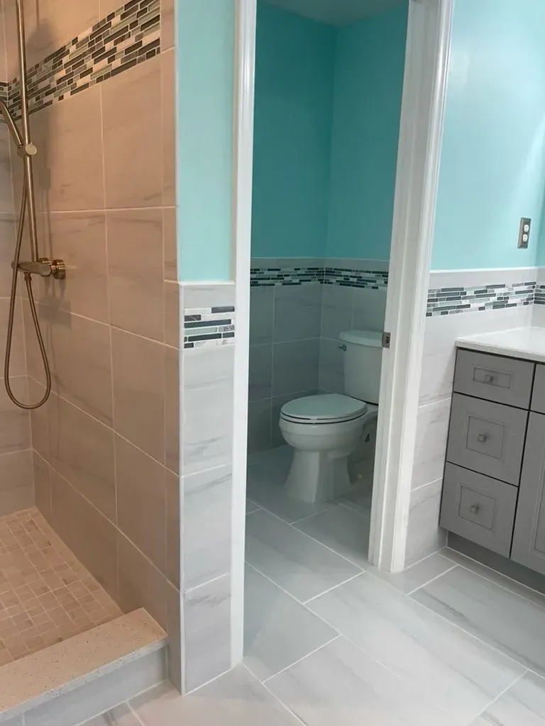 Bathroom with walk-in shower, toilet, and vanity in beige, white, and teal.