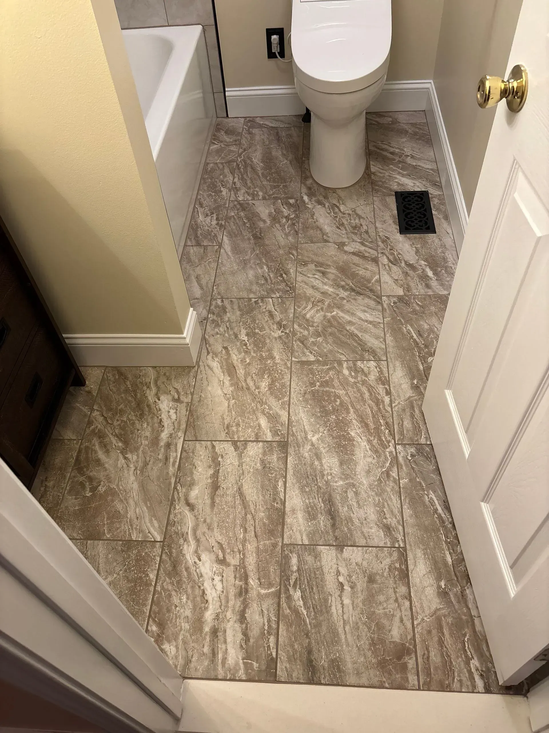 Small bathroom with white toilet, beige tile floor, and open door.