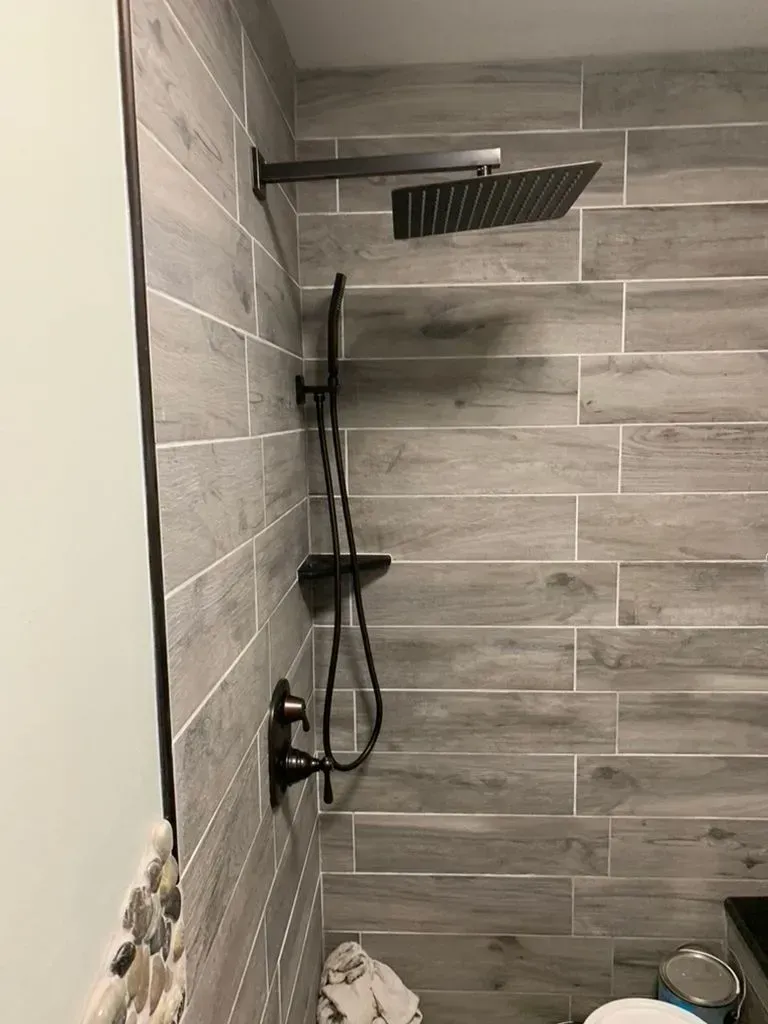 Modern shower with gray tile walls, black fixtures, and rainfall showerhead