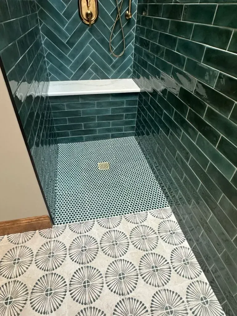 Teal-tiled shower with built-in bench and patterned white floor tiles