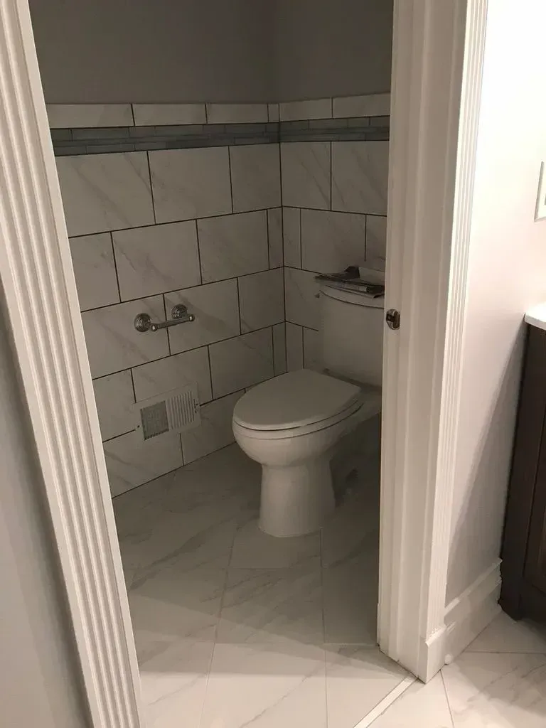 Small tiled bathroom with a toilet and wall-mounted sink