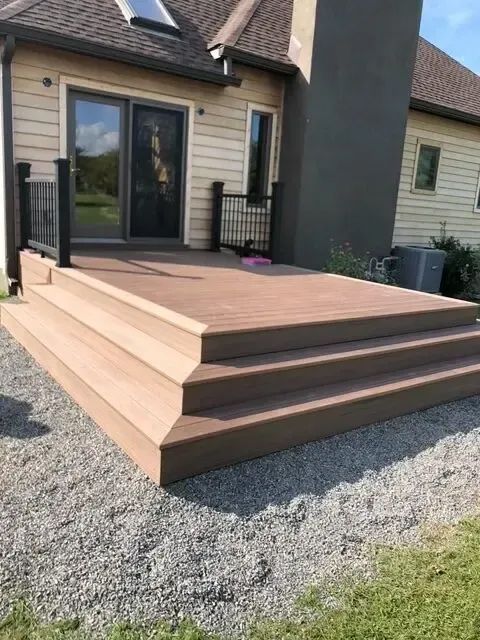 Three-tier wooden deck steps leading to a patio door on a house exterior