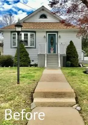 Small gray house with front steps, walkway, and a black lamp post in the yard.