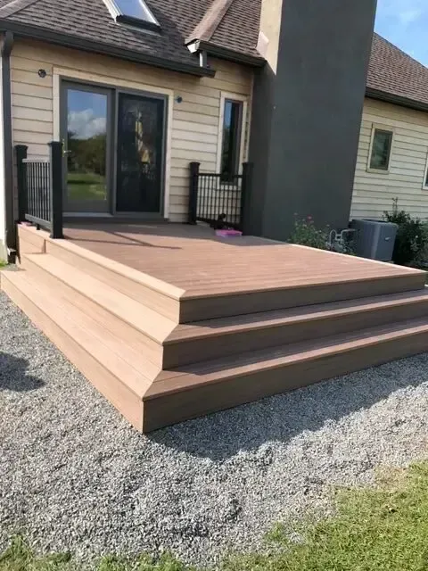 Modern house entrance with wide wooden steps leading to a patio door over gravel