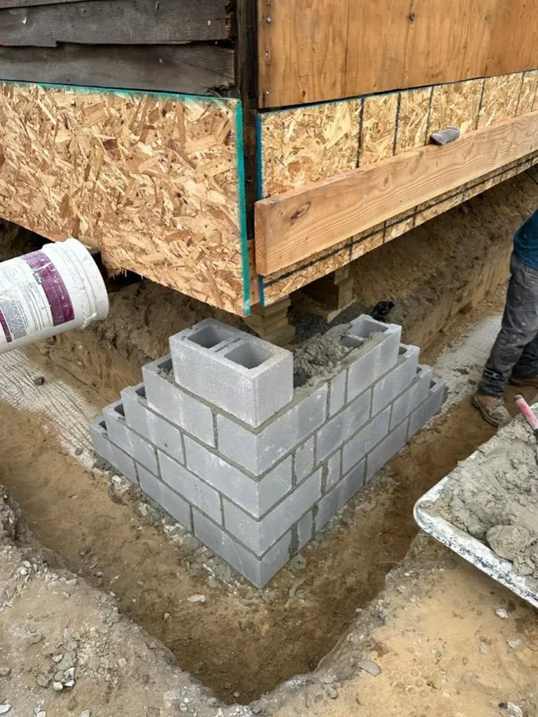 House corner on cinder blocks above a concrete pier during foundation repair