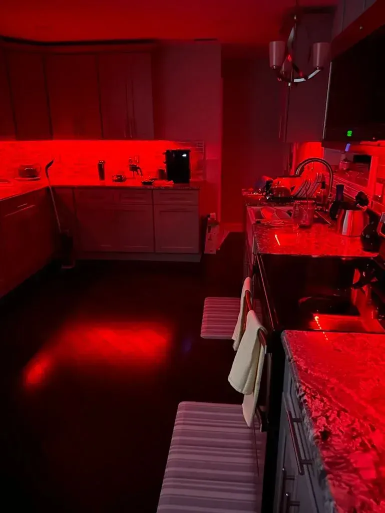 Red-lit kitchen with counters, sink, stove, and striped floor mats