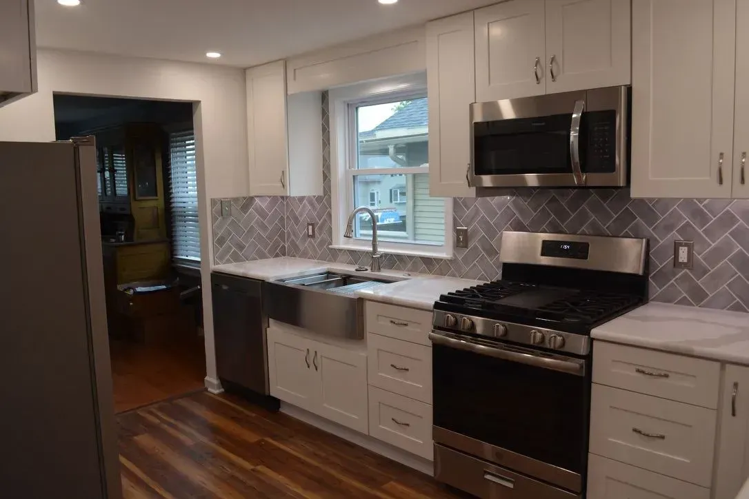 Modern kitchen with white cabinets, stainless steel appliances, and a window over the sink