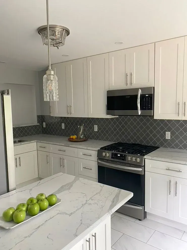 Bright white modern kitchen with marble island, stainless appliances, and green apples on the counter
