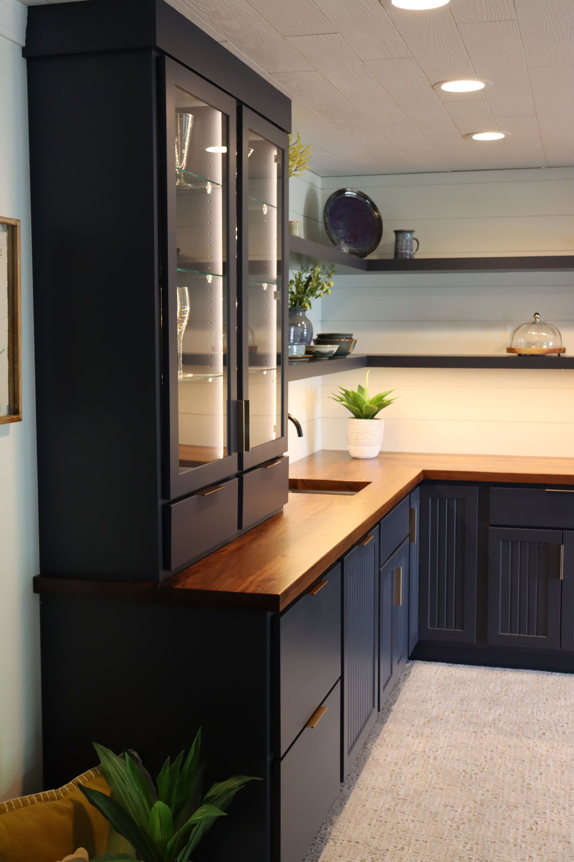 dark-colored kitchen cabinet with glass shelves and glass door