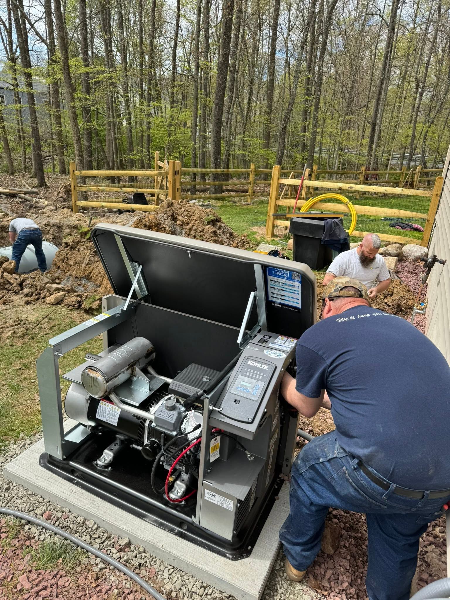 Workers inspecting open utility equipment in a wooded outdoor area