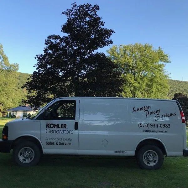 White KOHLER Generators service van parked on grass under trees, with Lancaster Power Systems logo and phone number.