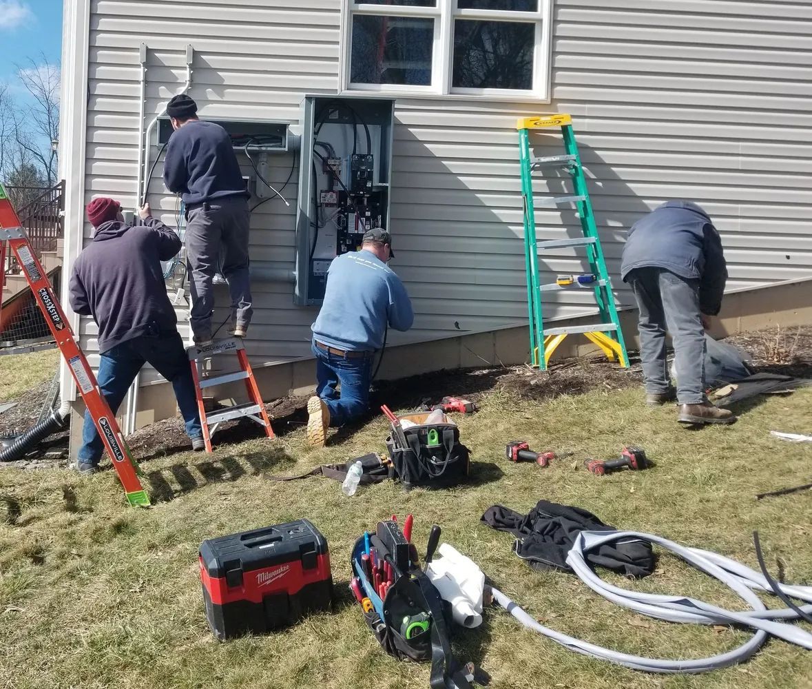 Workers using ladders and tools to repair the exterior of a house