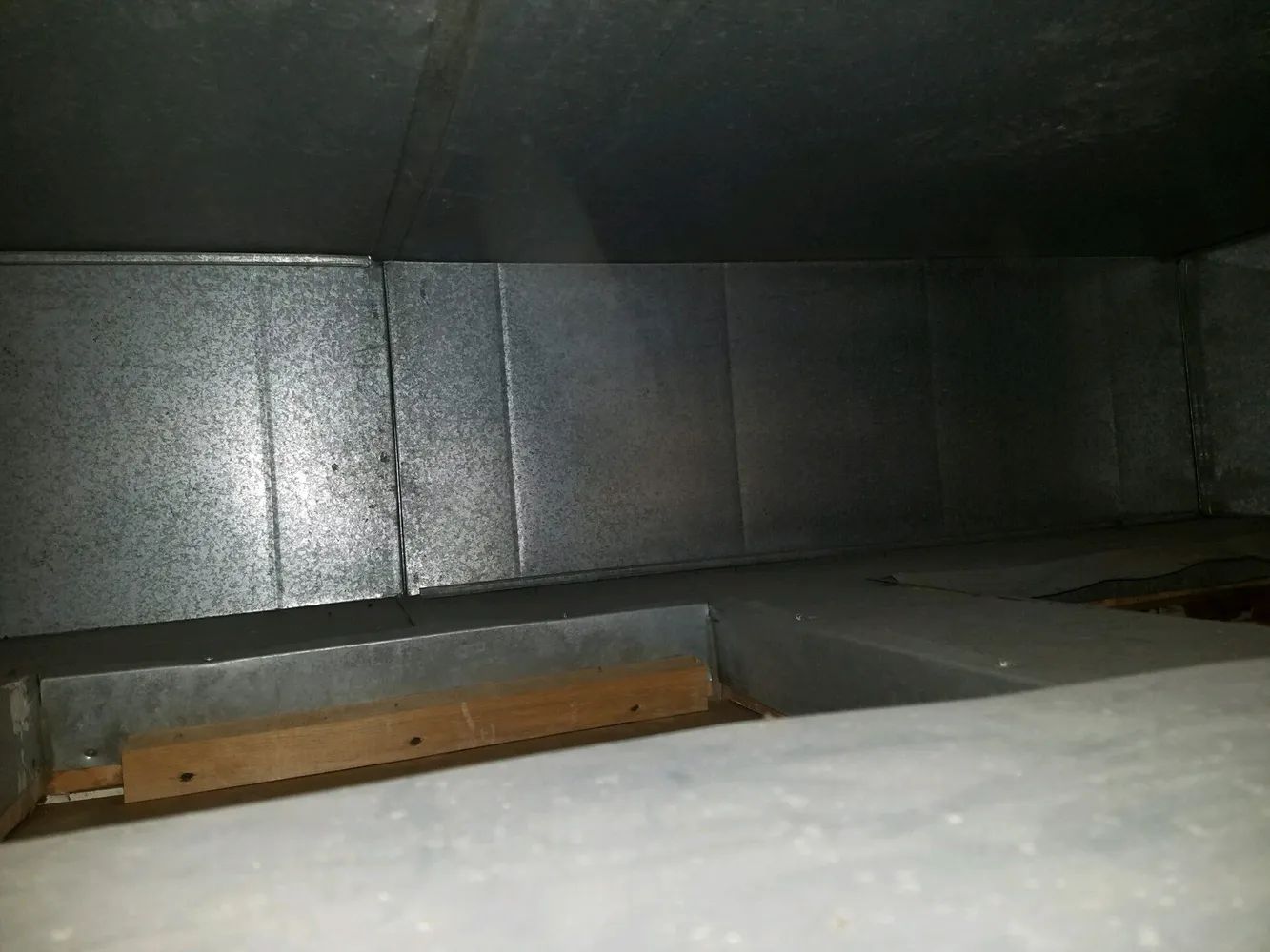 Metal duct interior with reflective panels and a white ledge in the foreground