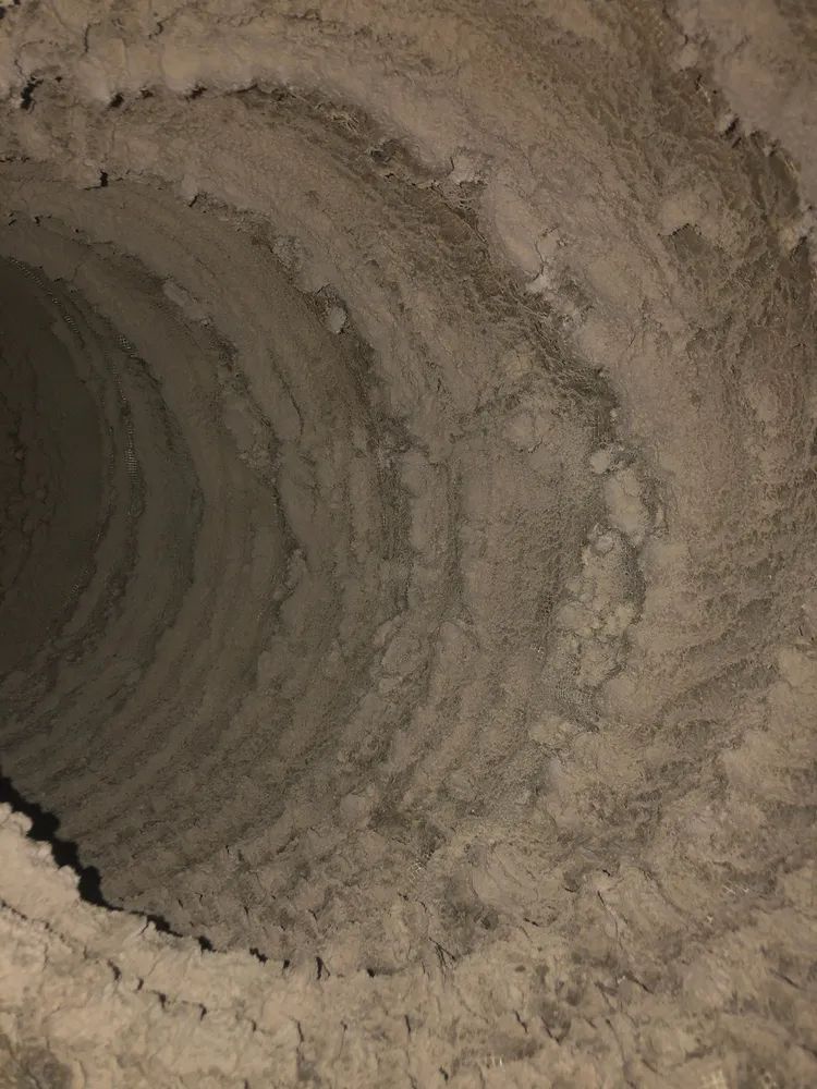 Close-up of a rough, circular dirt tunnel or hole with layered soil walls