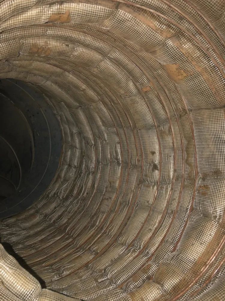 Close-up of a corrugated metal tunnel interior with concentric rusty rings
