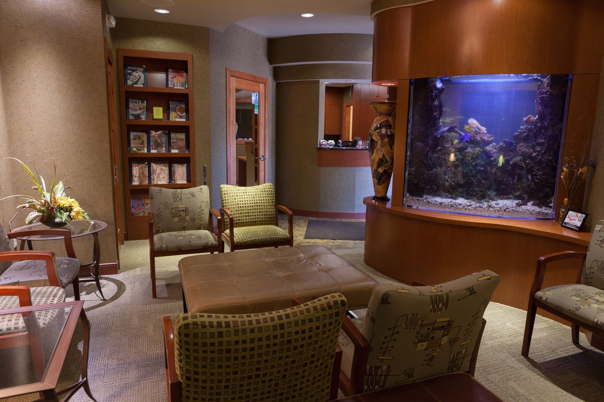 A waiting room with chairs, a table, and an aquarium.