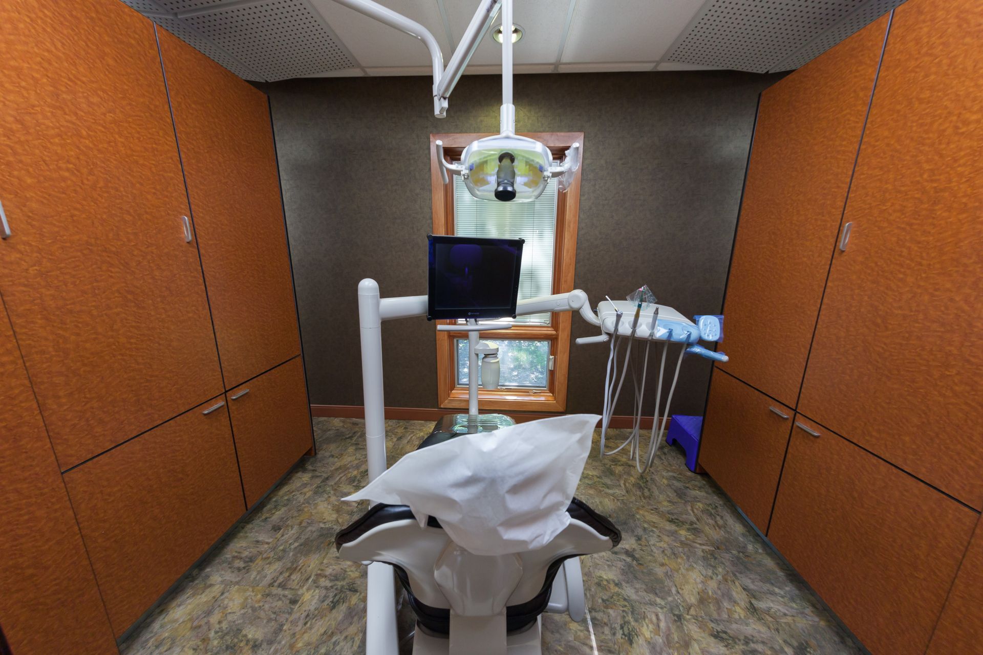 A dental office with a dental chair and a monitor.