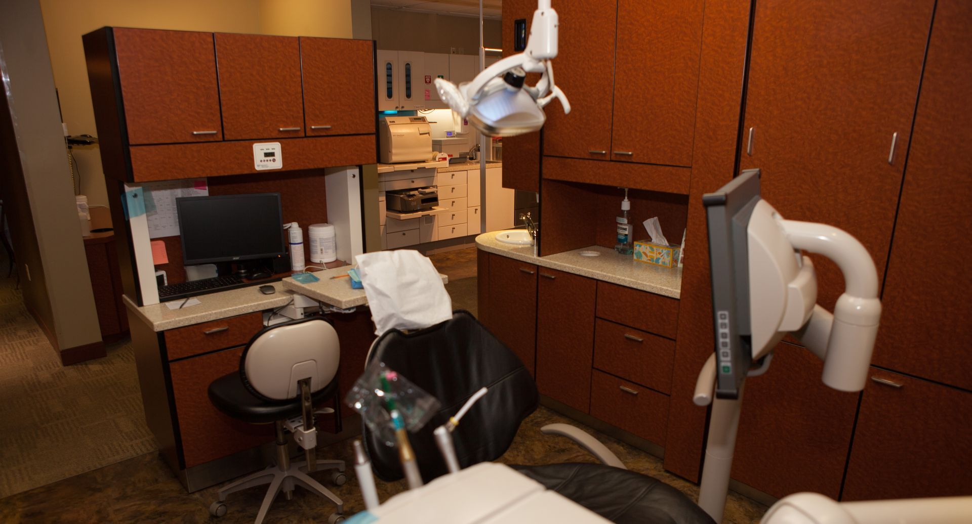 A dental office with a dental chair and a computer.