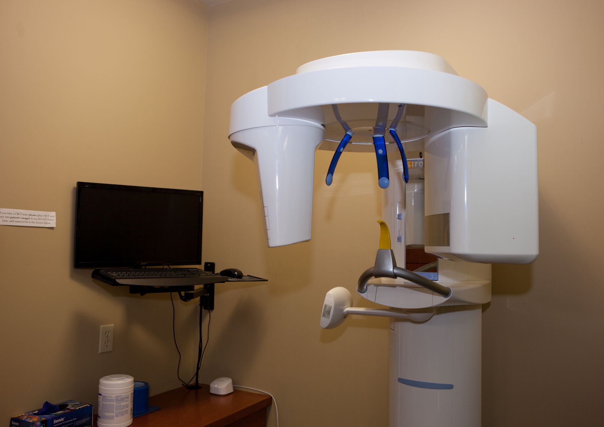 A room with a computer and a dental x-ray machine.