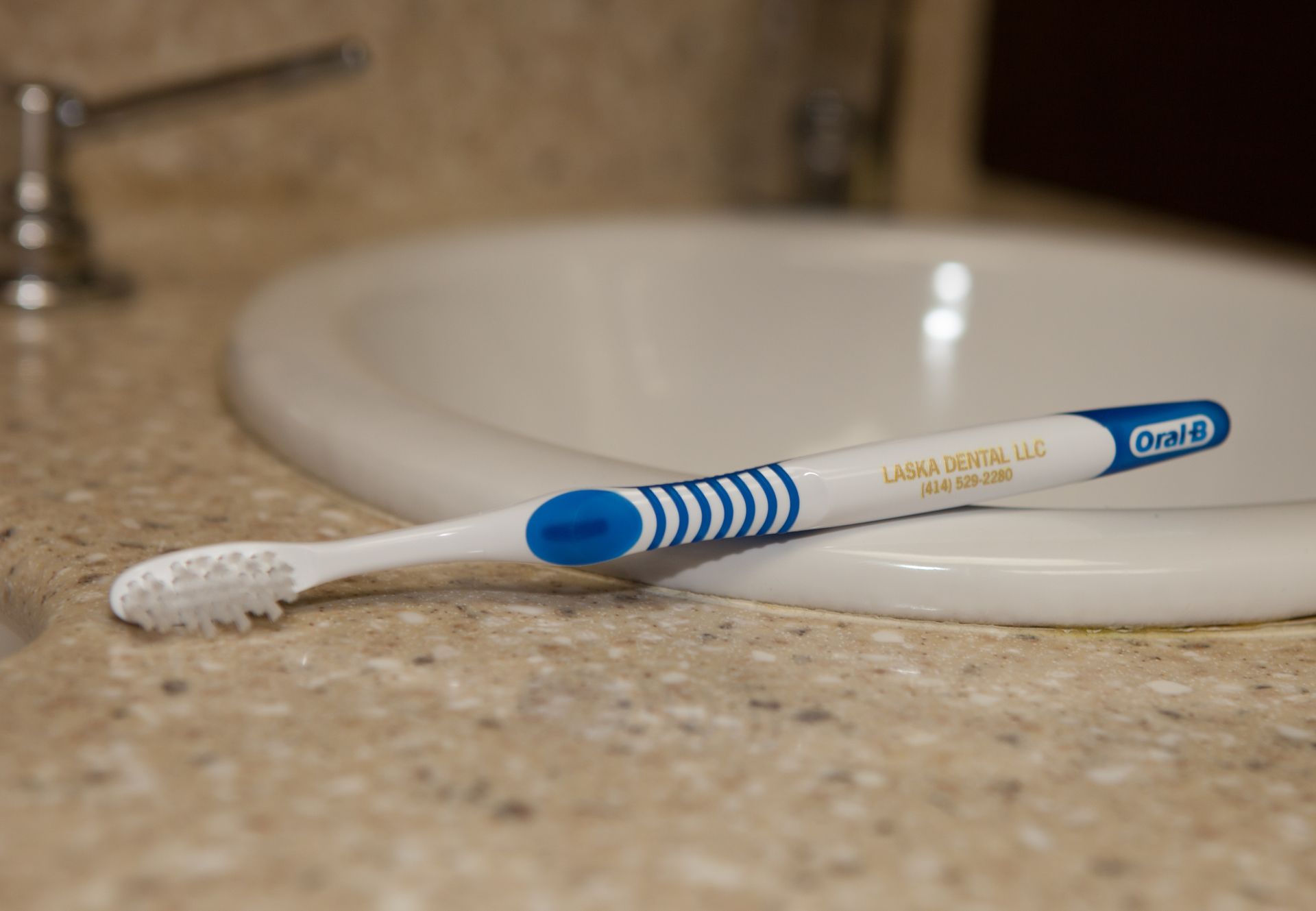 An oral b toothbrush is sitting on a bathroom counter next to a sink.