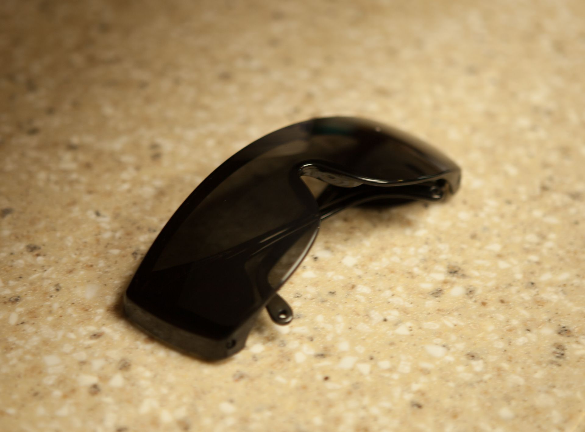 A pair of black sunglasses is laying on a table.
