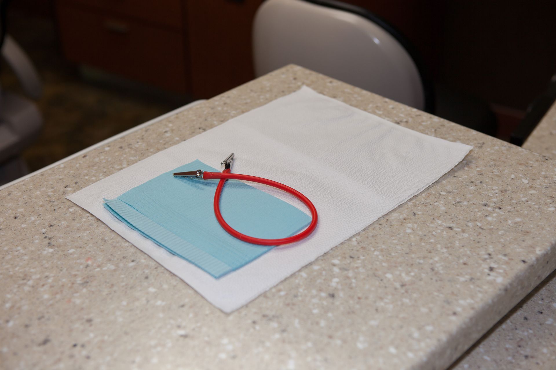 A red rubber band is laying on a piece of paper on a counter.