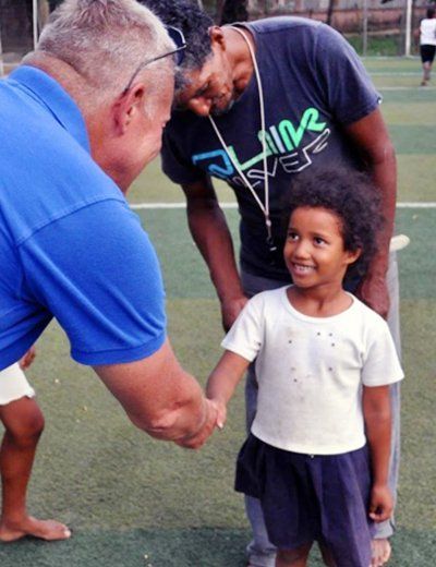 A man wearing a shirt that says shine ever shakes hands with a little girl