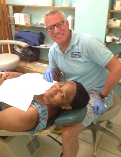 A man in a blue shirt is standing next to a child in a dental chair