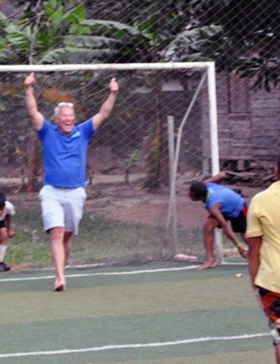 A man in a blue shirt is running on a soccer field