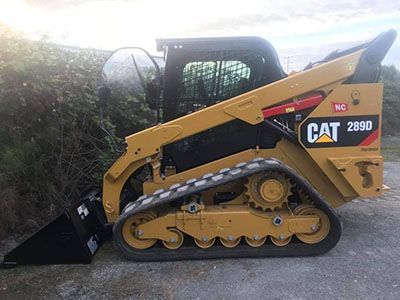 A cat skid steer loader is parked on the side of the road.