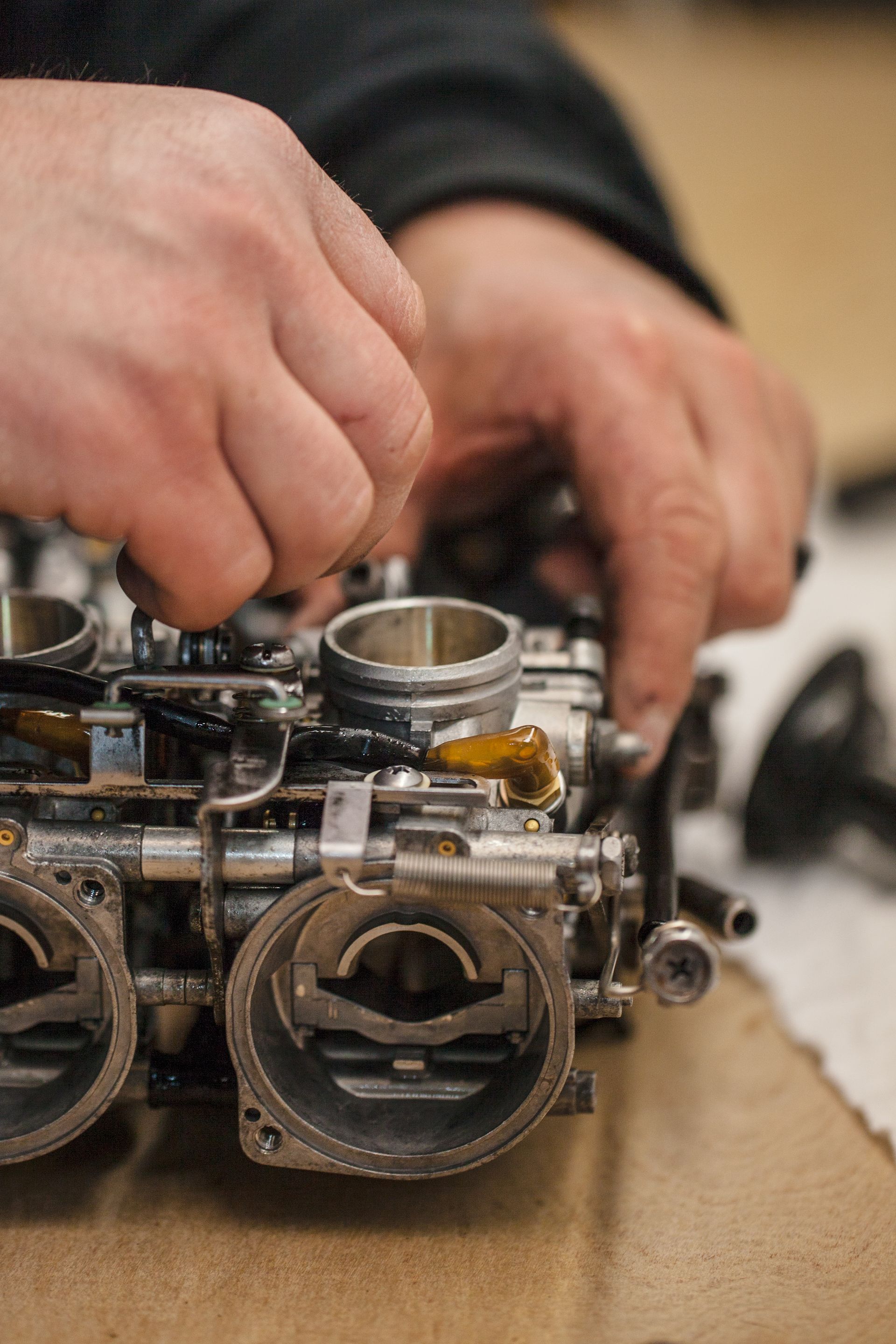 Hands working on a carburetor.