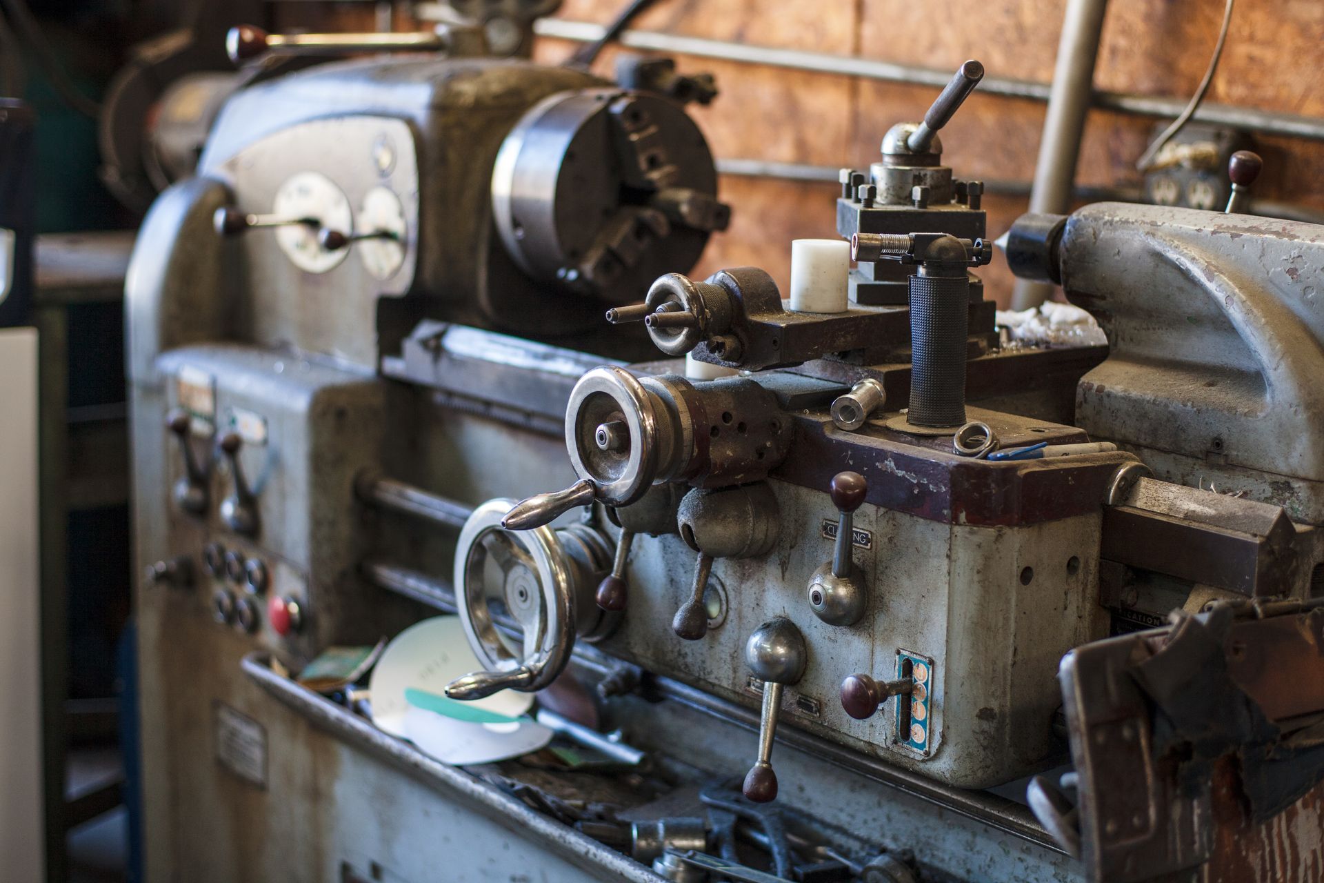 Old, dusty metal lathe in a workshop, with various knobs and levers.