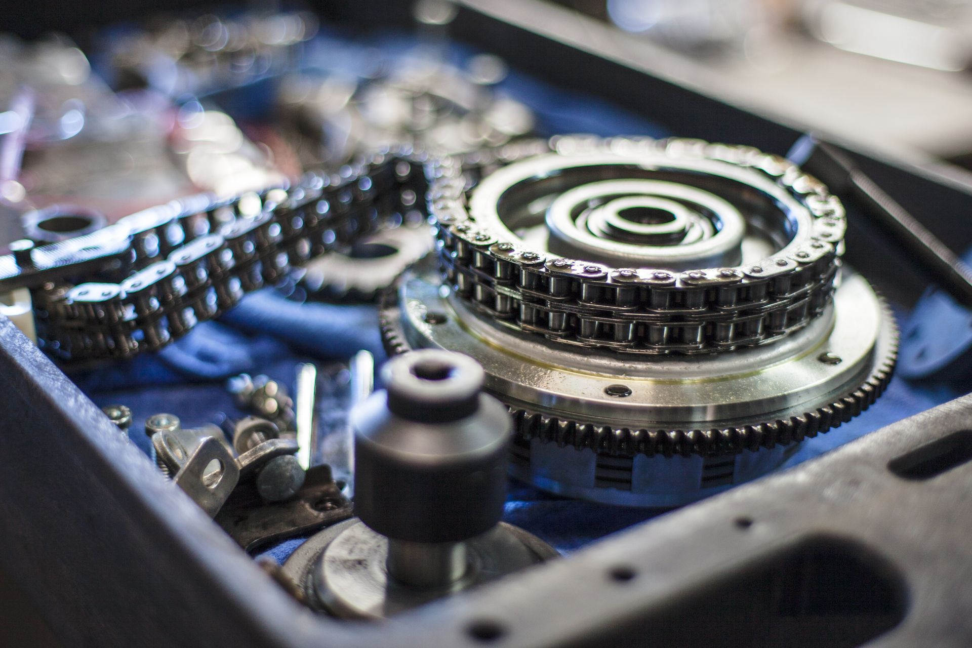 Close-up of motorcycle engine parts, including chains, gears, and a cylinder, in a toolbox.