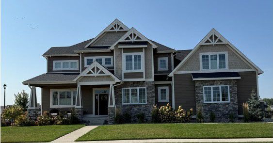 Two-story house with stone and brown siding, white trim, and a manicured lawn