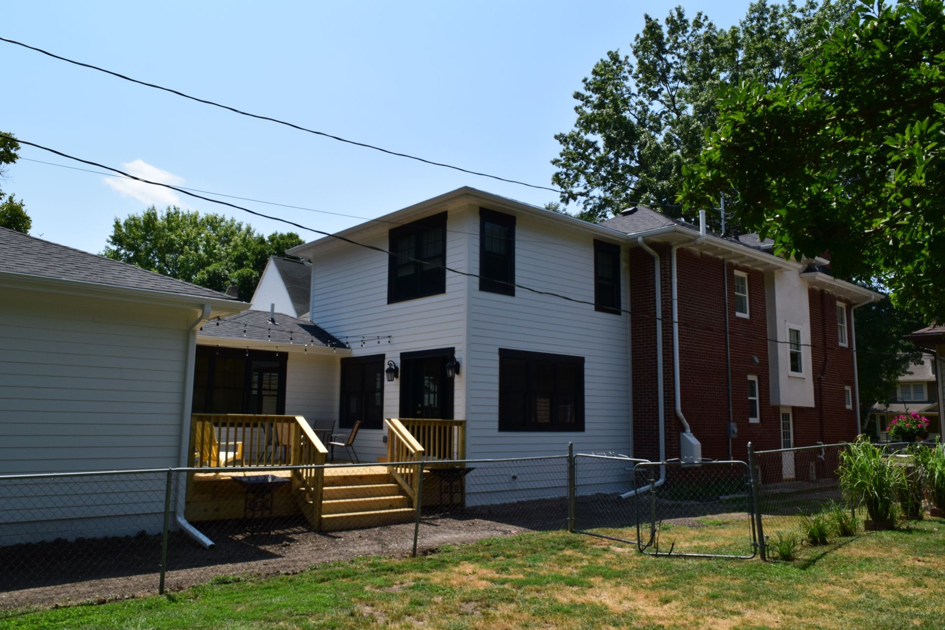 A brick house with a white siding and a wooden deck
