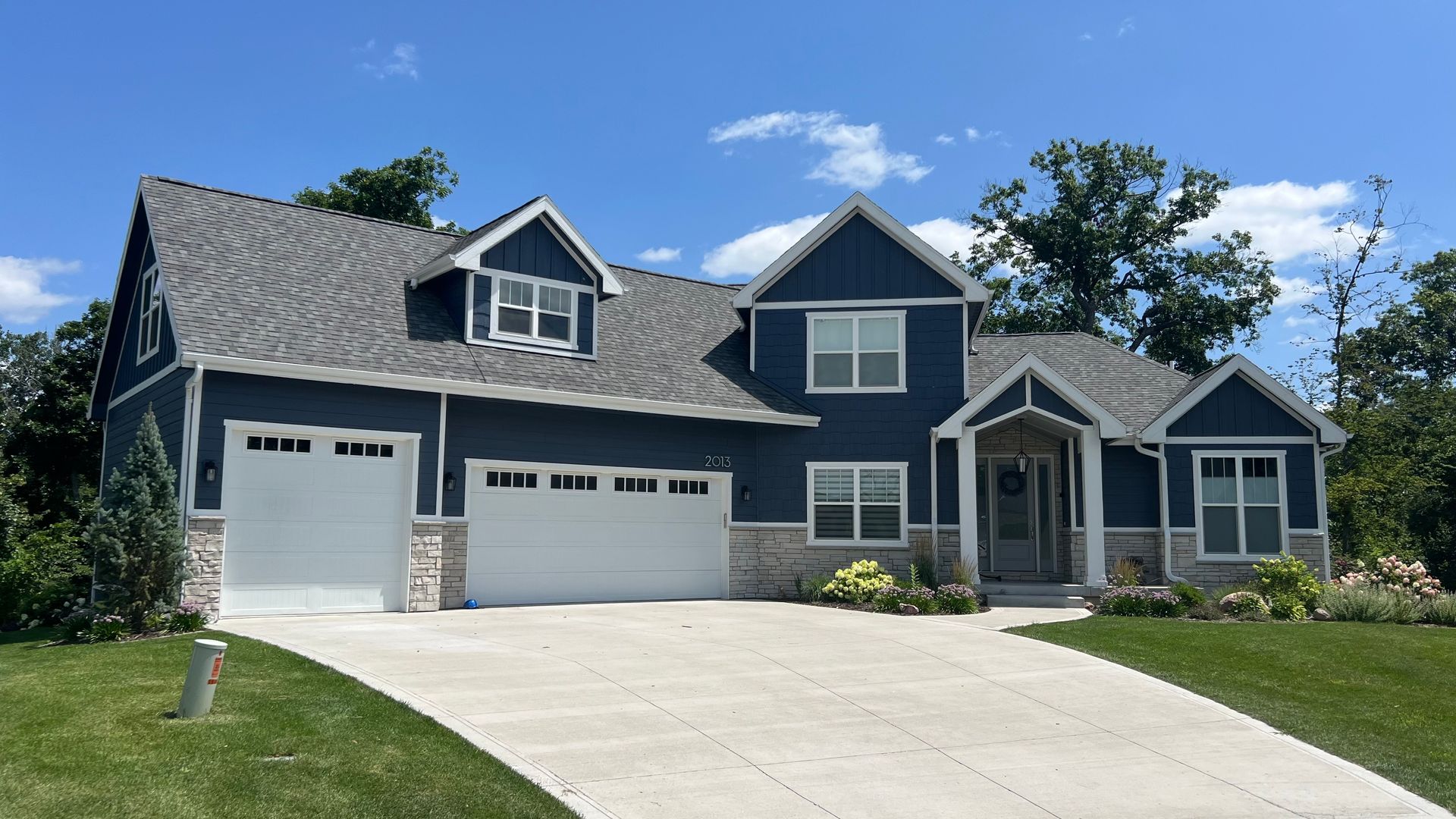 A blue house with a white garage door and a driveway