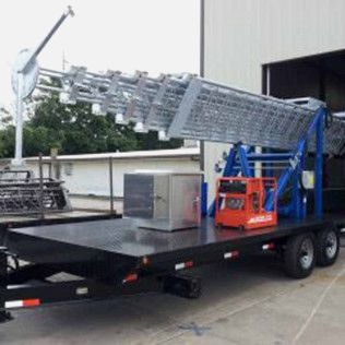 A trailer with a ladder on it is parked in front of a building.