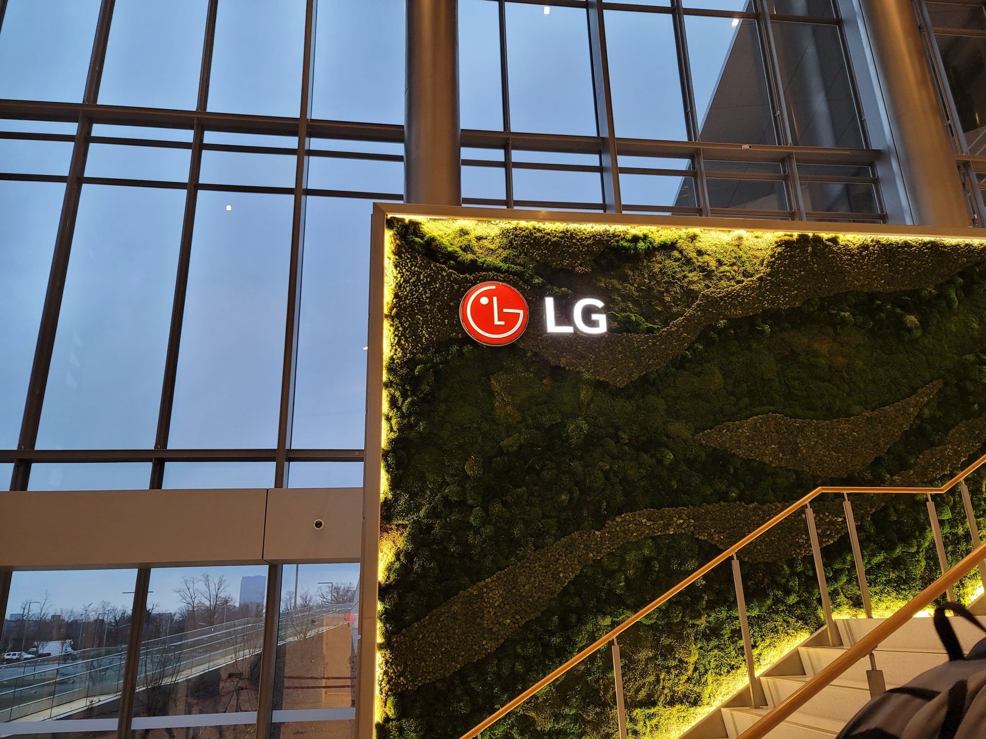 An lg sign is lit up in front of a green wall